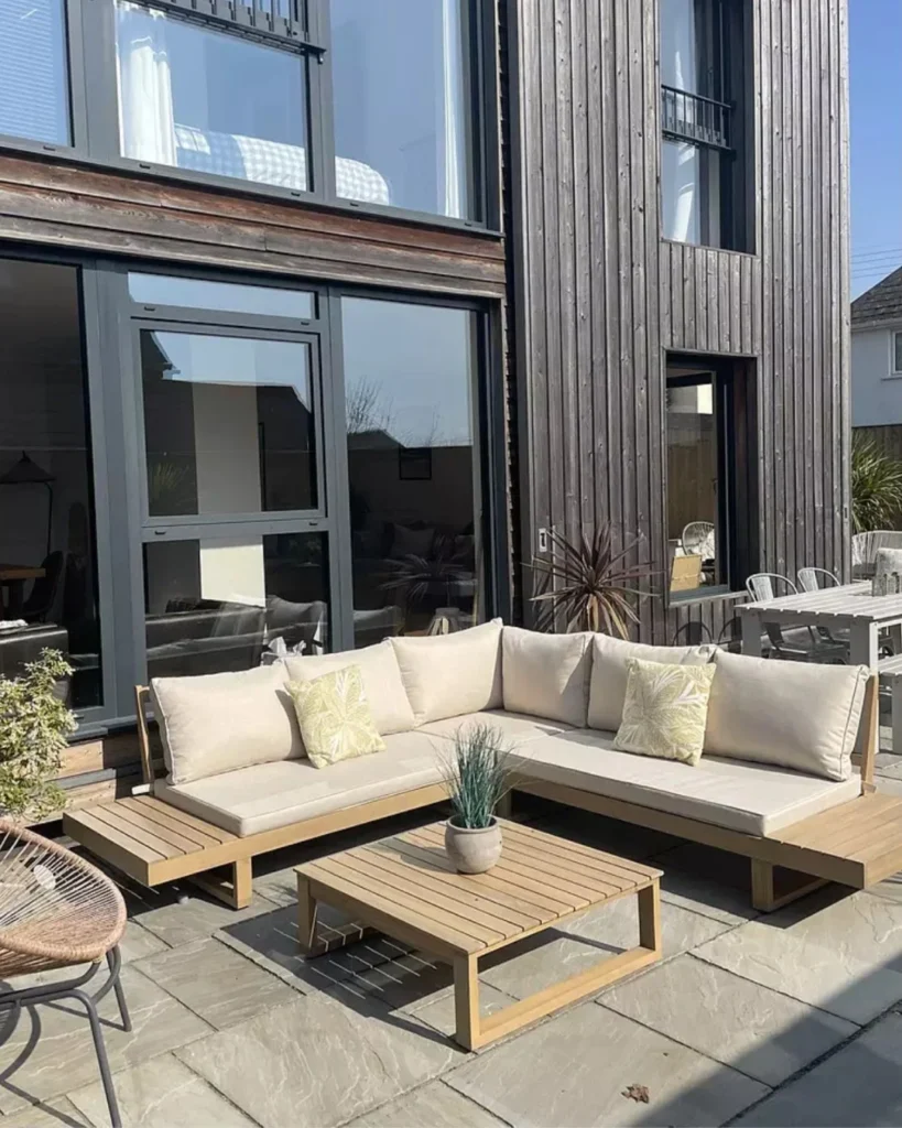 Teak Sectional Patio Setup with Charred Wood House Backdrop and Stone Paving